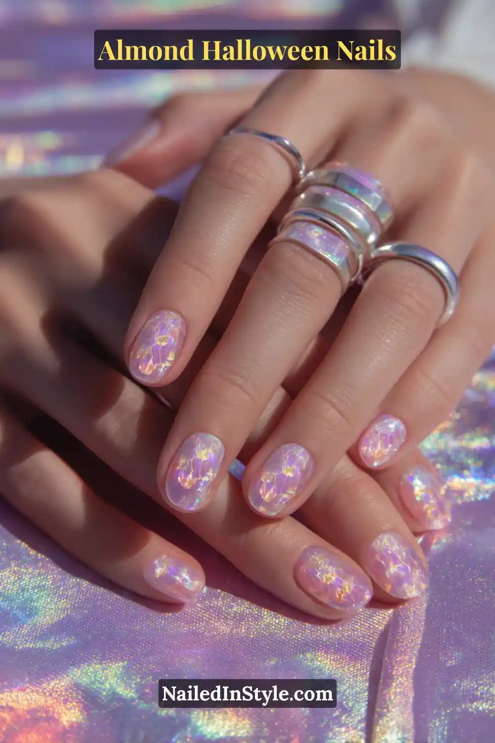 Close-up almond nails with holographic embedded pumpkin faces shimmering under translucent violet acrylic, high-gloss finish catching prismatic light, Almond Halloween Nails.