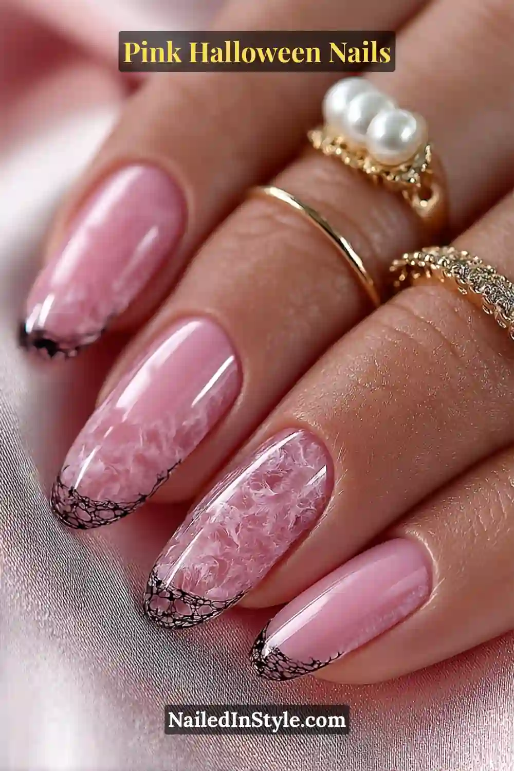 Pink Halloween nails with a sheer rose quartz base, delicate black web detailing on long almond nails, and soft glossy finish styled with gold and pearl rings.