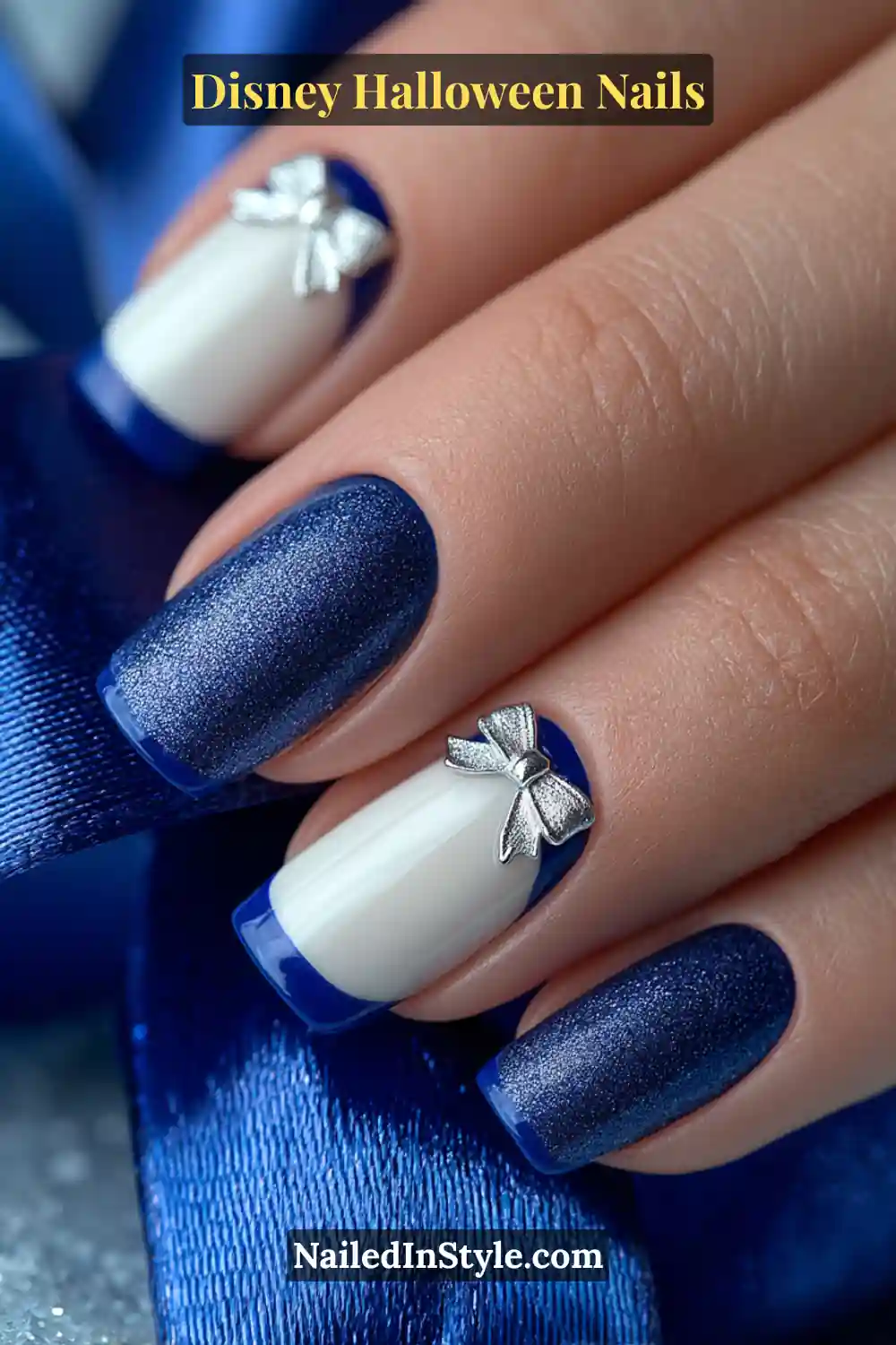 Medium squoval nails in glossy white with ultra-thin royal blue French tips and tiny 3D silver bows at the corners; paired with a satin blue ribbon for a polished Disney princess-inspired look.