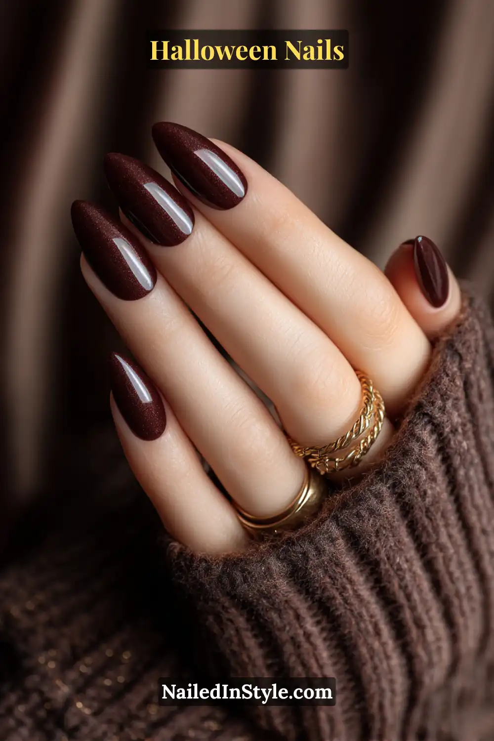 Almond and coffin-shaped nails in deep sable base with a narrow magnetic cat-eye beam on one accent nail per hand; glossy dimensional finish styled with layered gold rings and cozy knitwear, elegant Halloween nails for olive and deep skin tones.