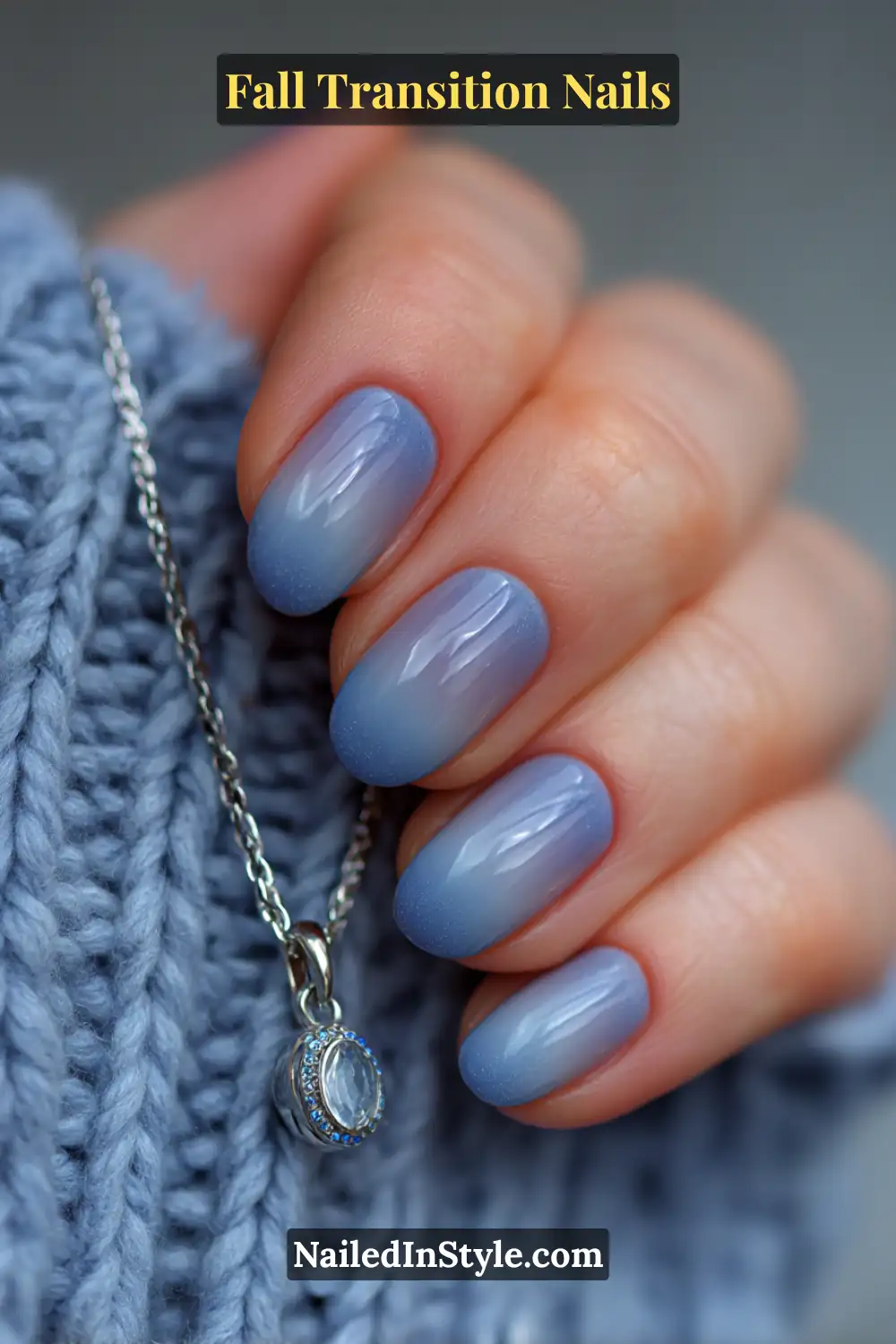 Medium oval nails featuring a soft sea-gray to dove gradient with a pearl undertone and matte finish, styled beside a silver pendant and knit sweater.