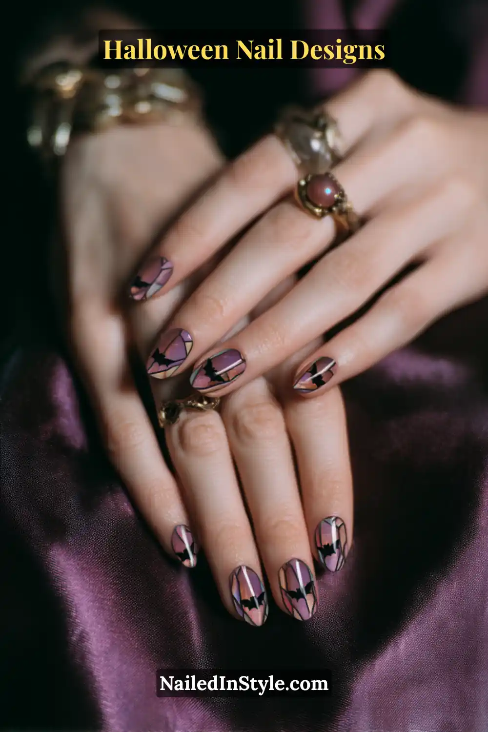 Close-up of oval nails with tiny black bat silhouettes surrounded by jewel-tone stained-glass color blocks in violet and rose shades, outlined in dark charcoal for a moody Halloween aesthetic.