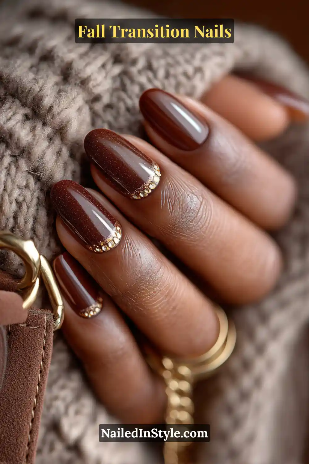Medium oval nails in deep truffle brown with a soft velvet finish, detailed with thin gold half-moon accents, styled beside a suede handbag.