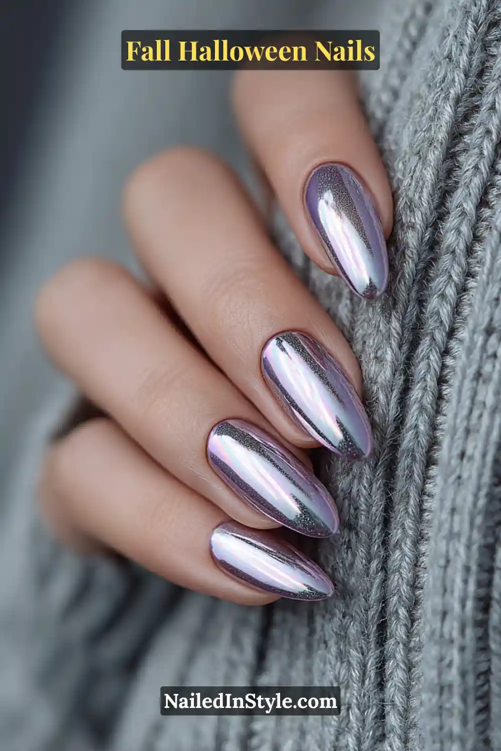 Medium almond nails featuring a mirrored chrome halo over a soft lavender core, glowing with subtle graphite undertones and styled against a cozy gray knit for a futuristic fall look.