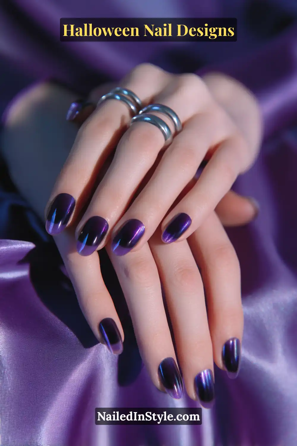Halloween Nail Designs Close-up of oval nails featuring a glowing black-violet aura design that fades into inky edges, styled with silver rings and deep purple satin for a cosmic Halloween look.