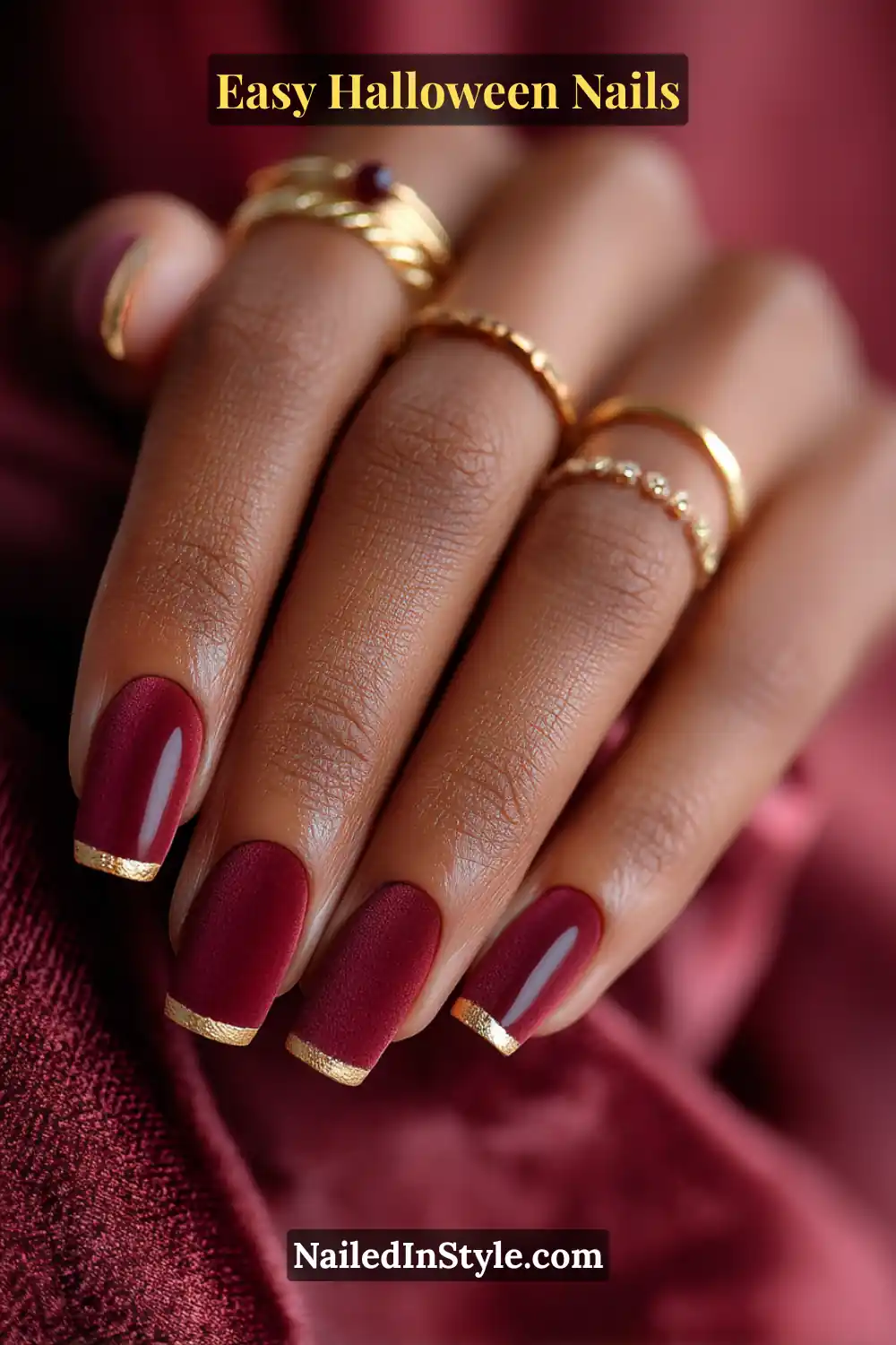 Almond nails in deep crimson matte with fine gold metallic cuffs at the tips, blending velvet texture and shimmer for Easy Halloween Nails.