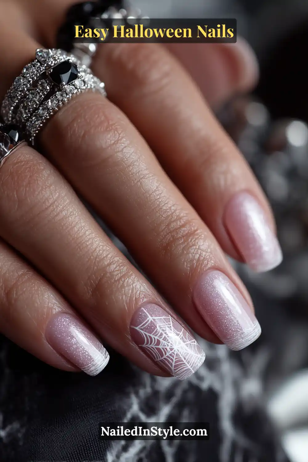 Squoval nails with a pale pink shimmer base featuring a fine white spiderweb design delicately placed in one corner, detailed ink linework for Easy Halloween Nails.
