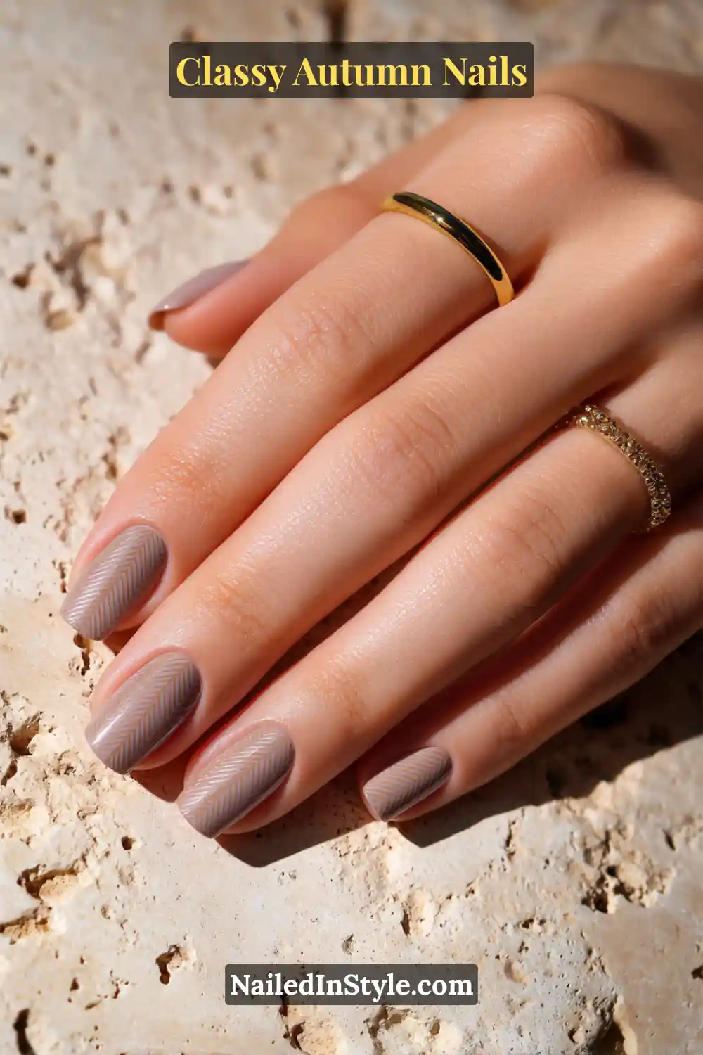 Neutral autumn nails with a camel base and subtle herringbone micro-stamping in stone taupe, styled with gold rings.