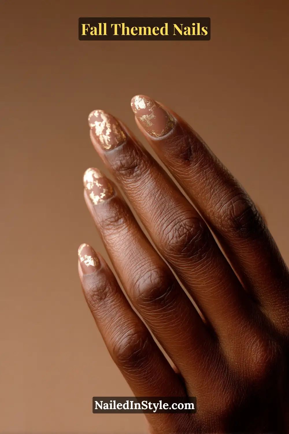 Almond fall nails with cacao base and antique gold foil halo at cuticle, flattering on deep skin.