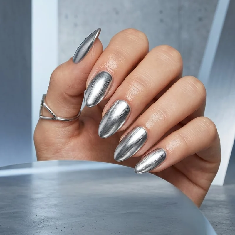 A hand displaying almond-shaped nails with a highly reflective metallic silver chrome finish for February nail ideas.