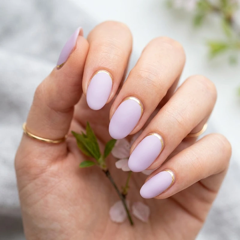 Matte lavender nails with thin gold metallic accents at the cuticle.