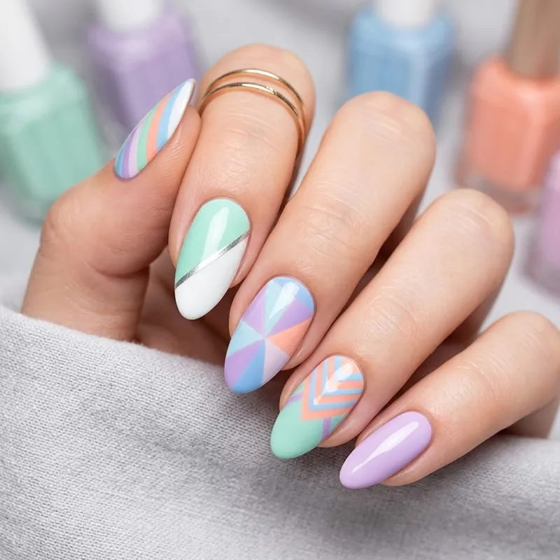 Artistic geometric nail art using pastel purple, blue, and orange shades.