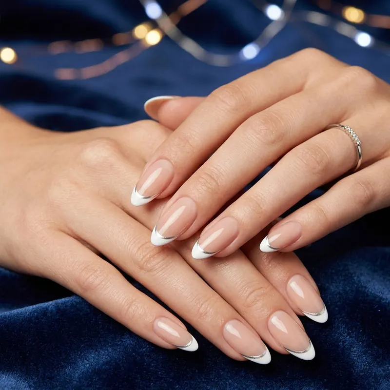 Prom Nails: Your Ultimate Guide to Stunning Styles and Techniques 2026 4 A close-up of almond-shaped prom nails featuring a minimalist French tip design with a glossy nude base, a crisp white tip, and a thin metallic silver micro-line accent against a blue velvet background.