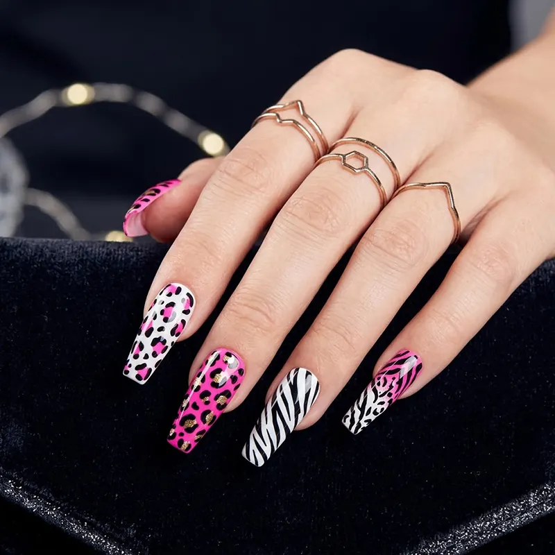 Prom Nails: Your Ultimate Guide to Stunning Styles and Techniques 2026 18 A close-up of long coffin-shaped prom nails showcasing bold high-contrast animal prints, featuring alternating neon pink leopard spots with gold glitter accents and stark black-and-white zebra stripes, accessorized with rose gold rings against a black velvet clutch.