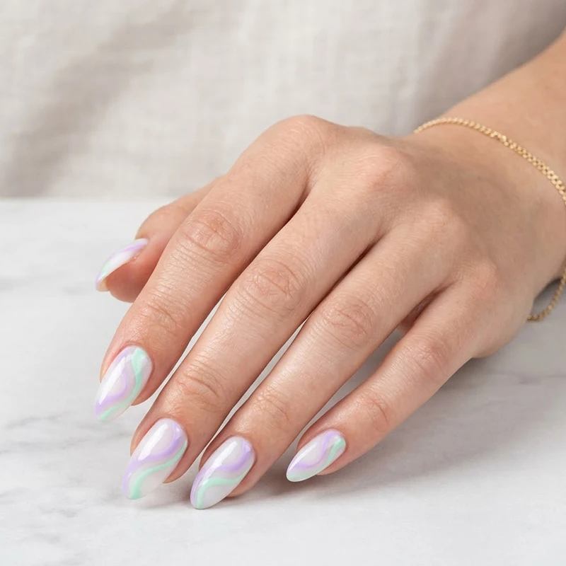 Professional beauty shot of almond nails featuring pastel lavender and mint green abstract swirls over a milky white base, showcasing modern preppy summer nails.
