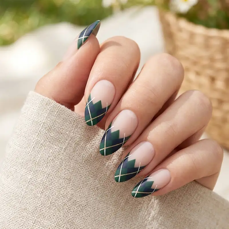 Professional close-up of medium almond nails featuring a clear base coat and a sophisticated dark green and navy blue argyle pattern on the tips with a matte finish.